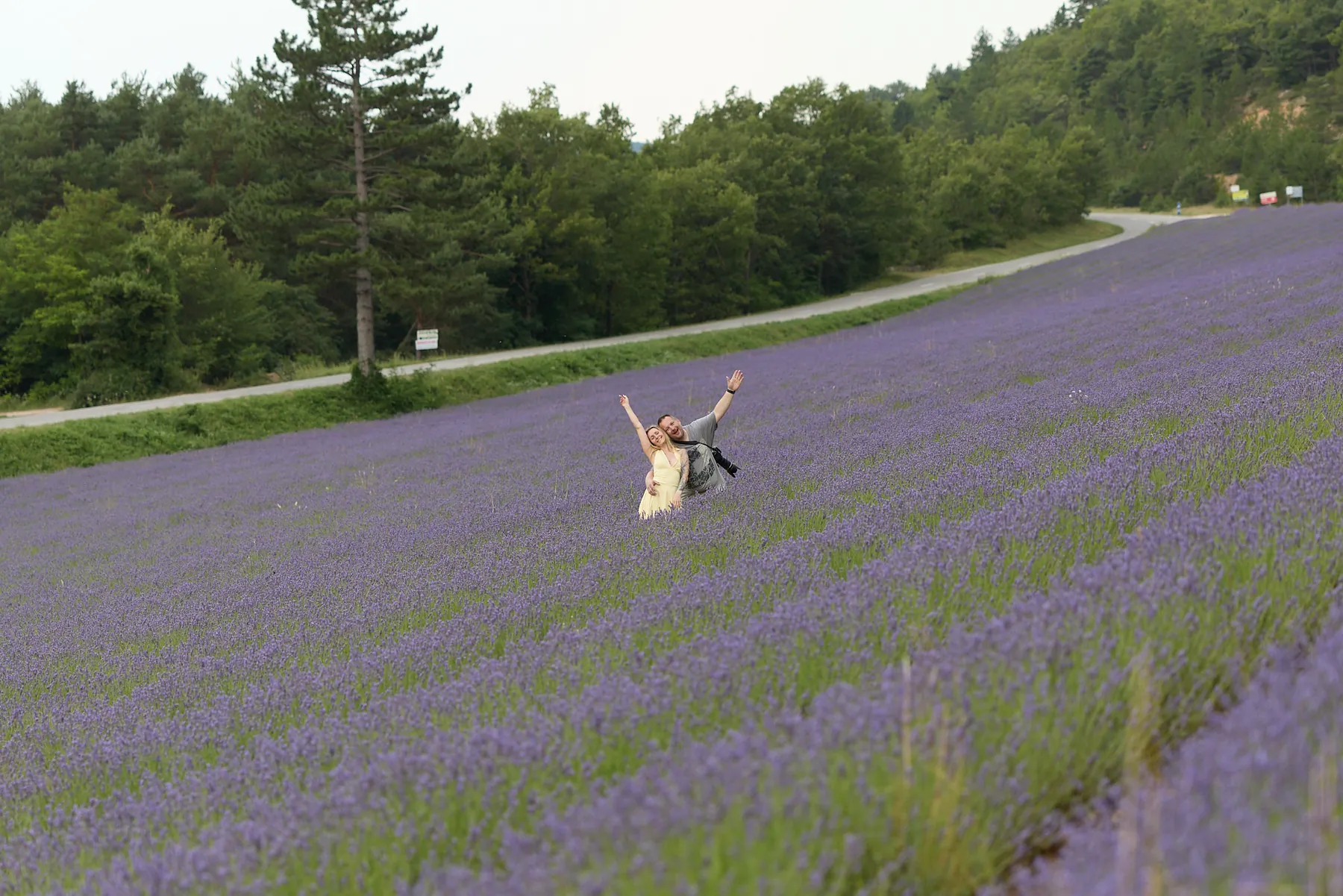 Fotograf und Model jubeln mit erhobenen Armen mitten in einem Lavendelfeld