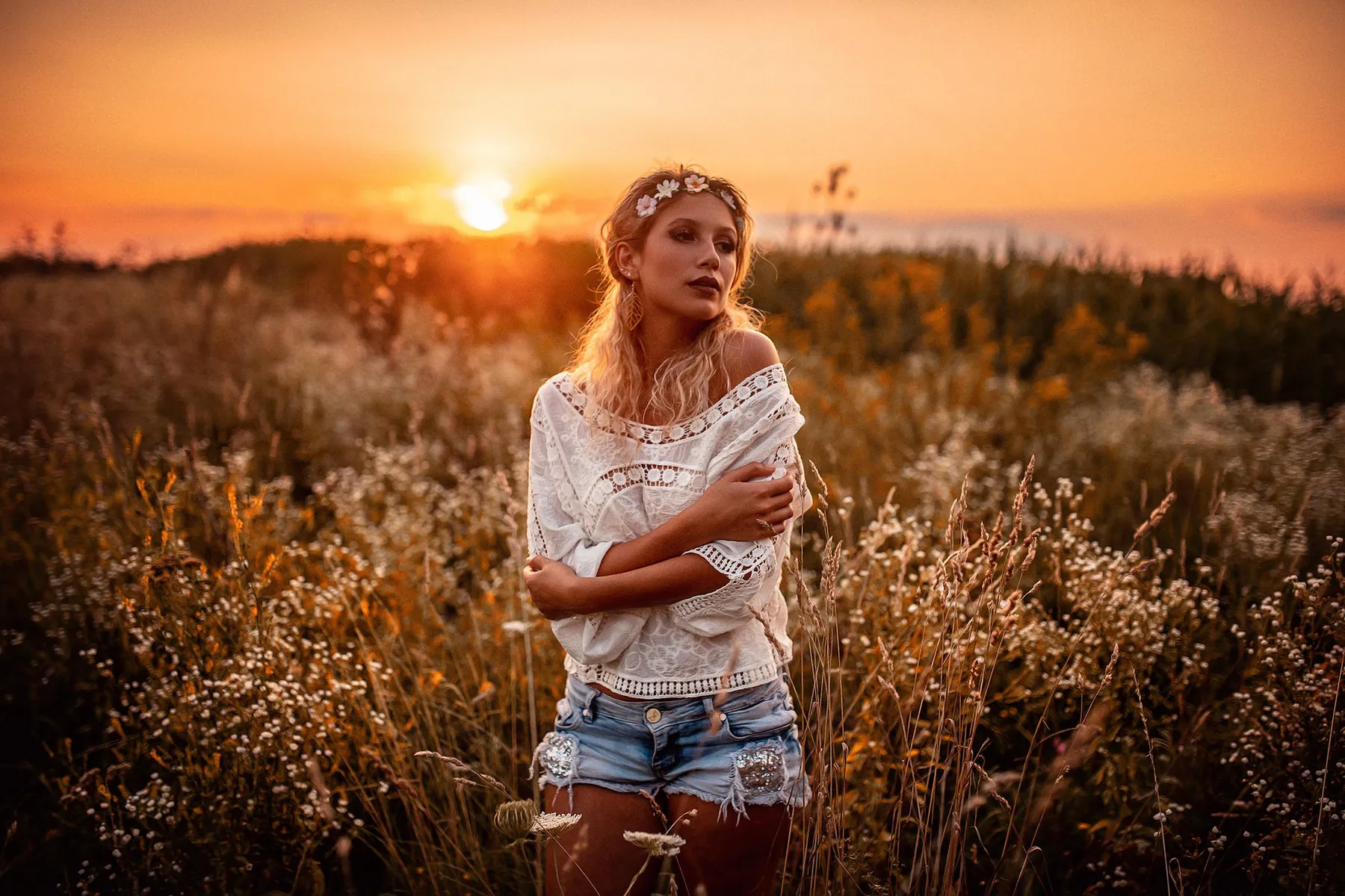 Woman in a light top in a meadow at sunset