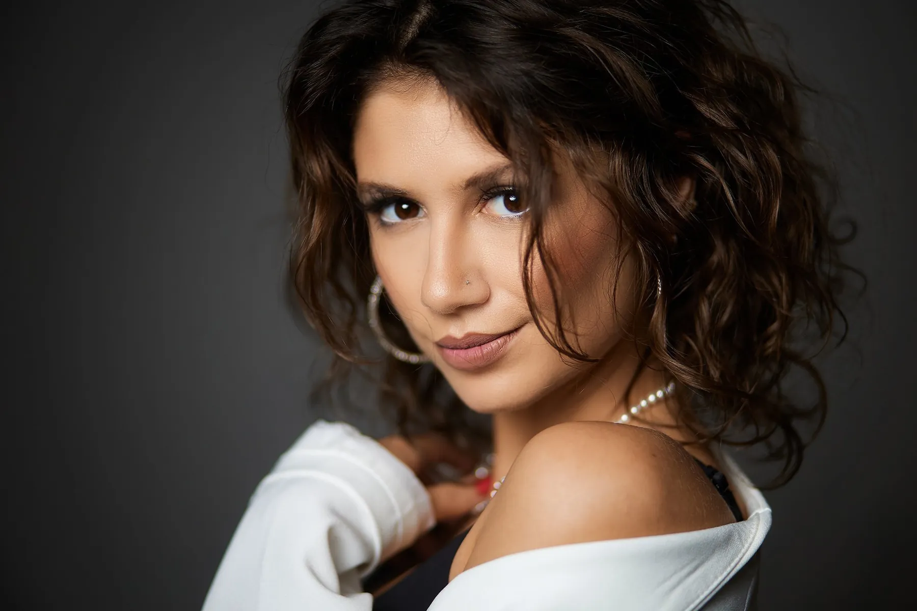Portrait of a woman with dark curls and a white top