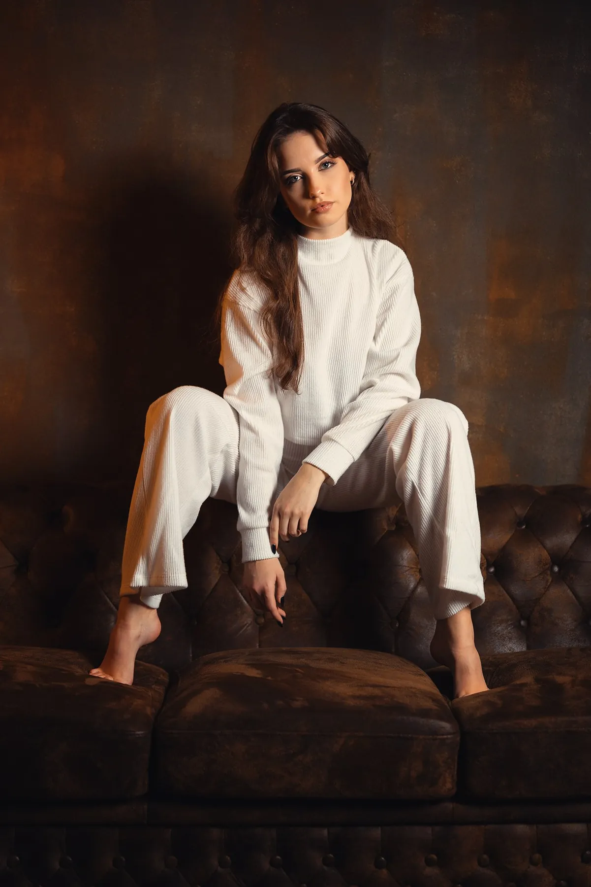 Model in white on a Chesterfield sofa