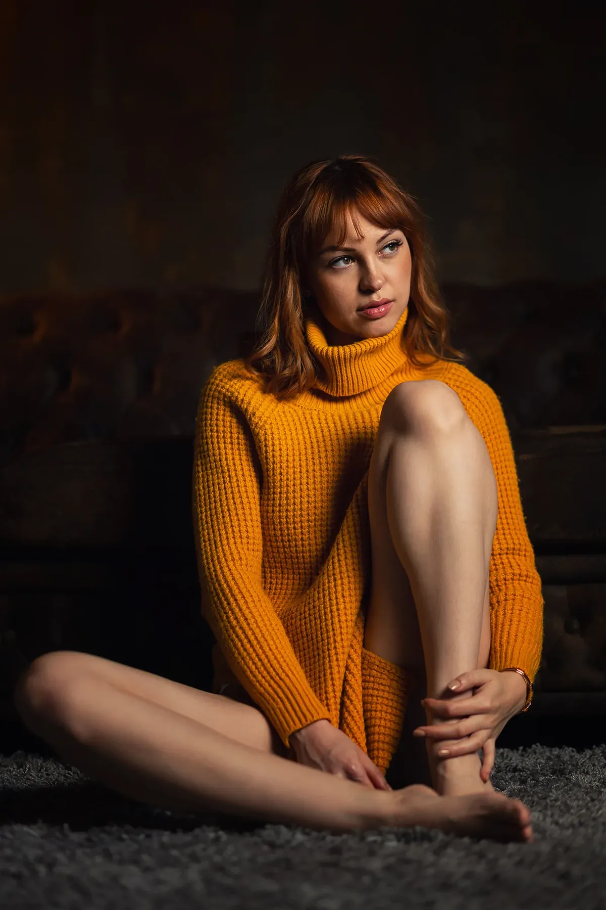 Red-haired woman in an orange polo-neck jumper in the studio