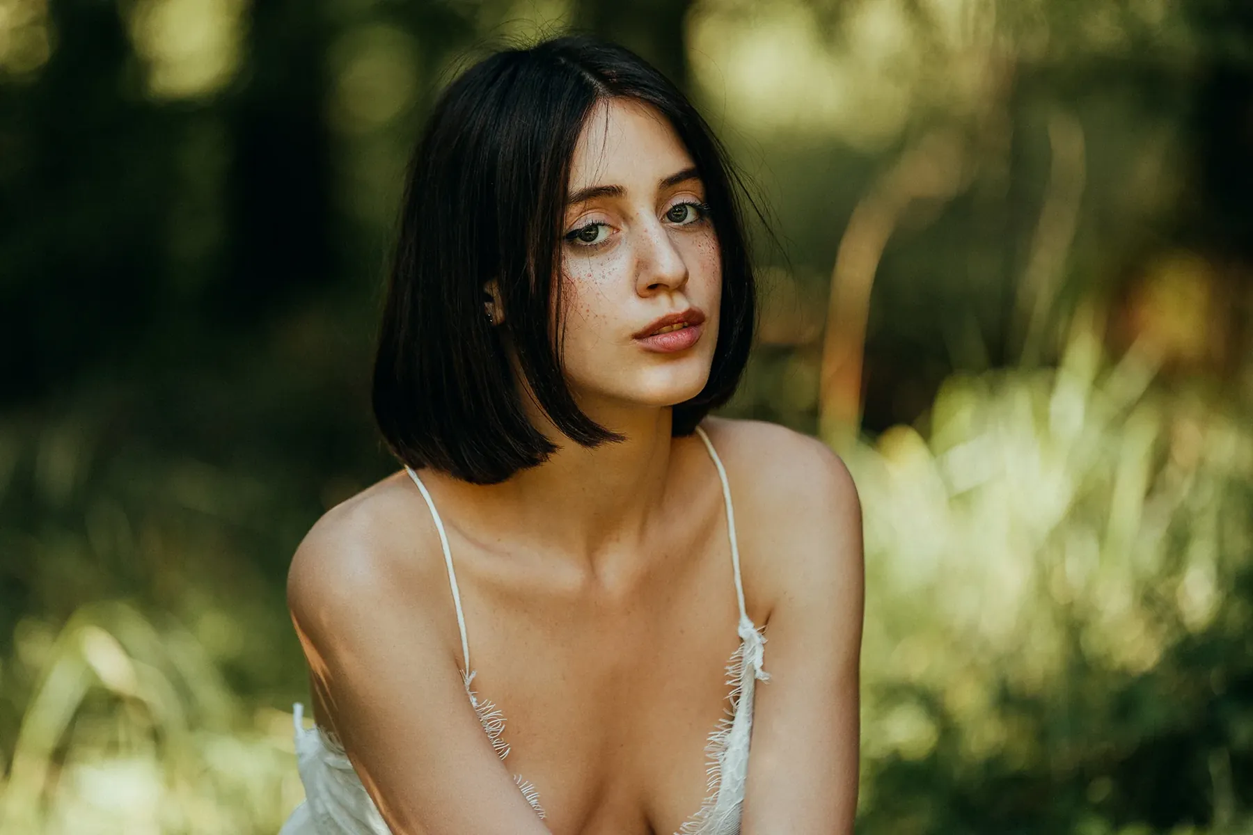 Portrait of a woman with short dark hair surrounded by greenery