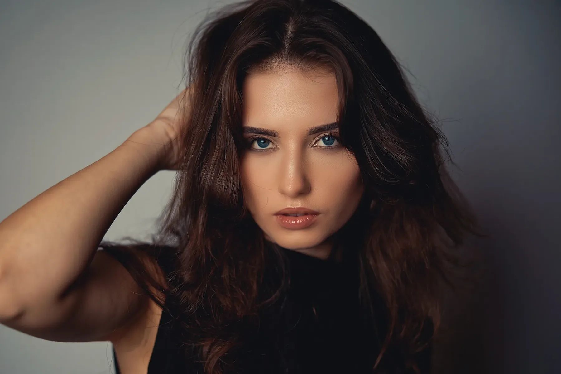 Portrait of a woman with dark hair against a grey background